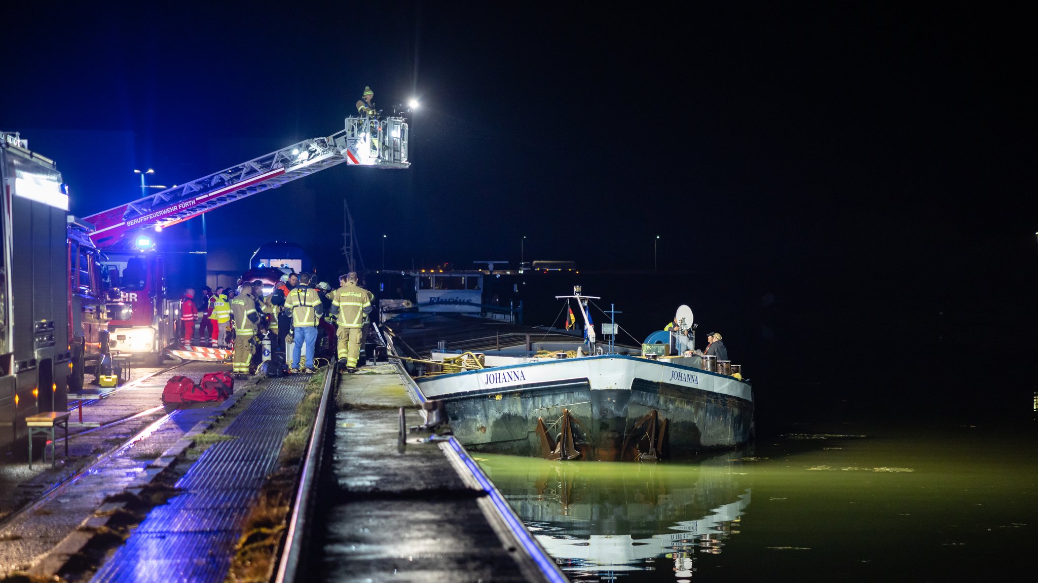 Einsatzkräfte der Feuerwehr und Polizei untersuchen das havarierte Frachtschiff, das im Fürther Hafen liegt.