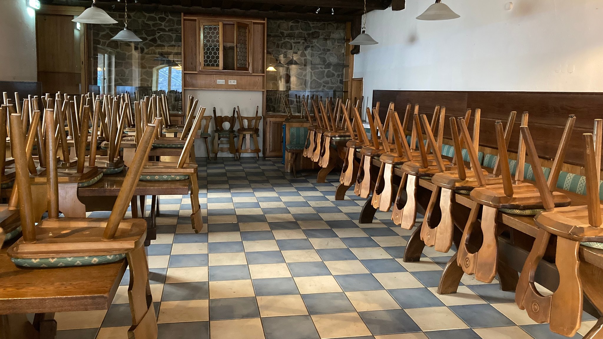 Die Gaststube im Wirtshaus, Stühle sind auf den Tischen gelagert.