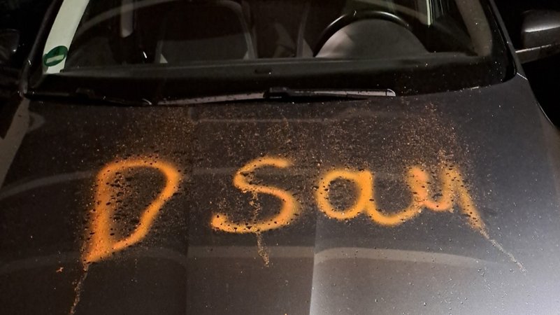 Schwarzes Auto mit der orangefarbenen Aufschrift "Sau". | Bild: Christine Hammerschick Schwarzes Auto mit der orangefarbenen Aufschrift "Sau".