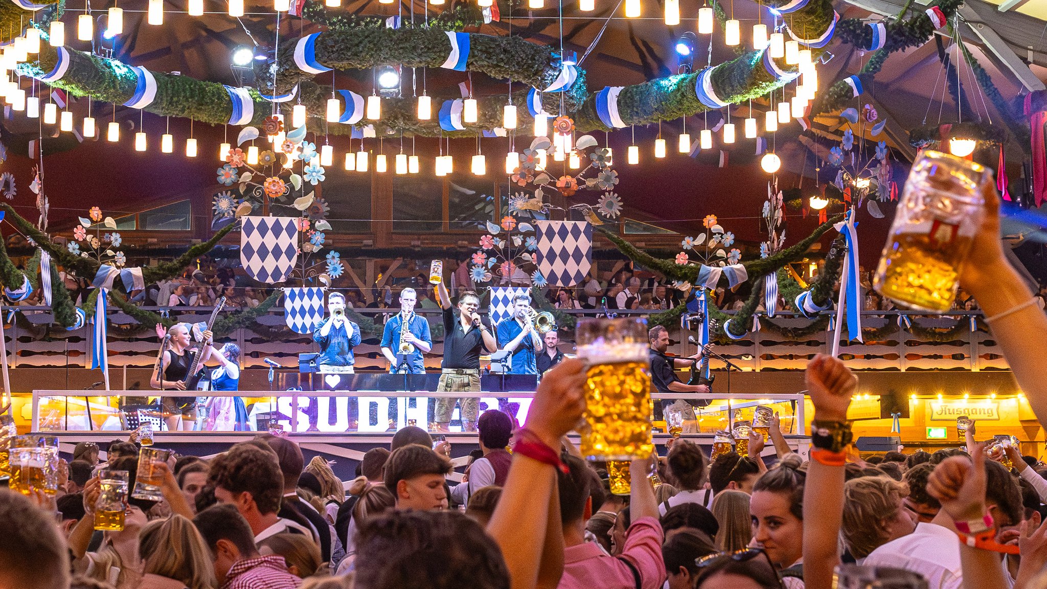 Die Band "Südherz" auf der Bühne der Schottenhamel-Festhalle, im Vordergrund feiernde Besucher. | Bild: Südherz Die Band "Südherz" auf der Bühne der Schottenhamel-Festhalle, im Vordergrund feiernde Besucher.