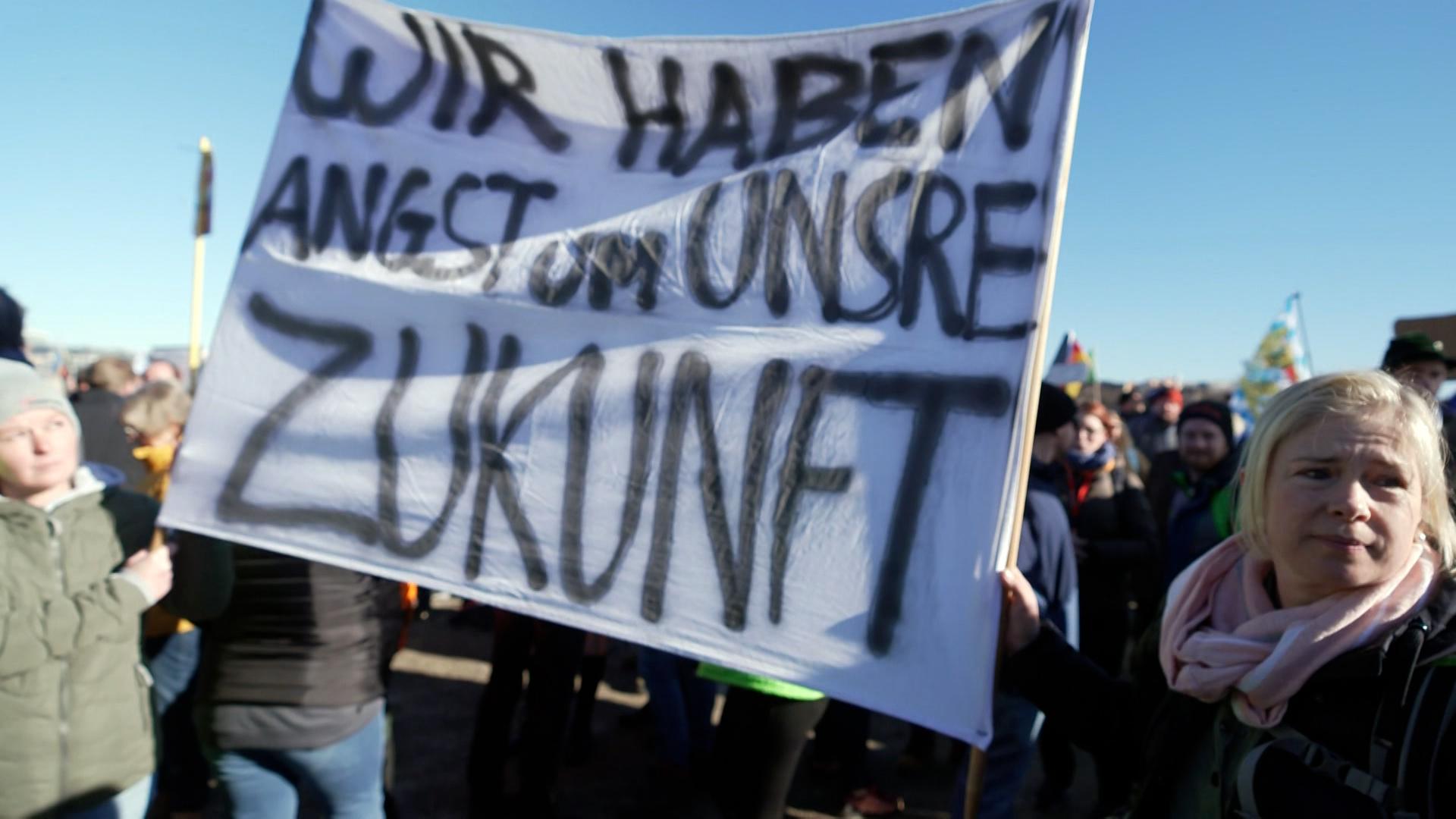 Zu sehen sind Protestierende mit Spruchbändern.