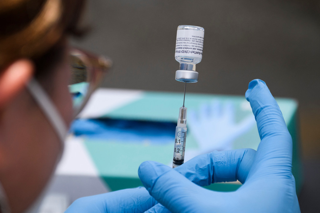 Frau zieht Impfstoff von Biontech/Pfizer in eine Spritze (Symbolbild)
