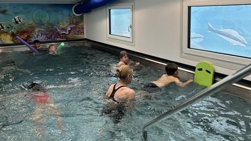 In einem kleinen Schwimmbecken bringt eine Frau Kindern das Schwimmen bei. | Bild: BR/Kristina Kreutzer In einem kleinen Schwimmbecken bringt eine Frau Kindern das Schwimmen bei.