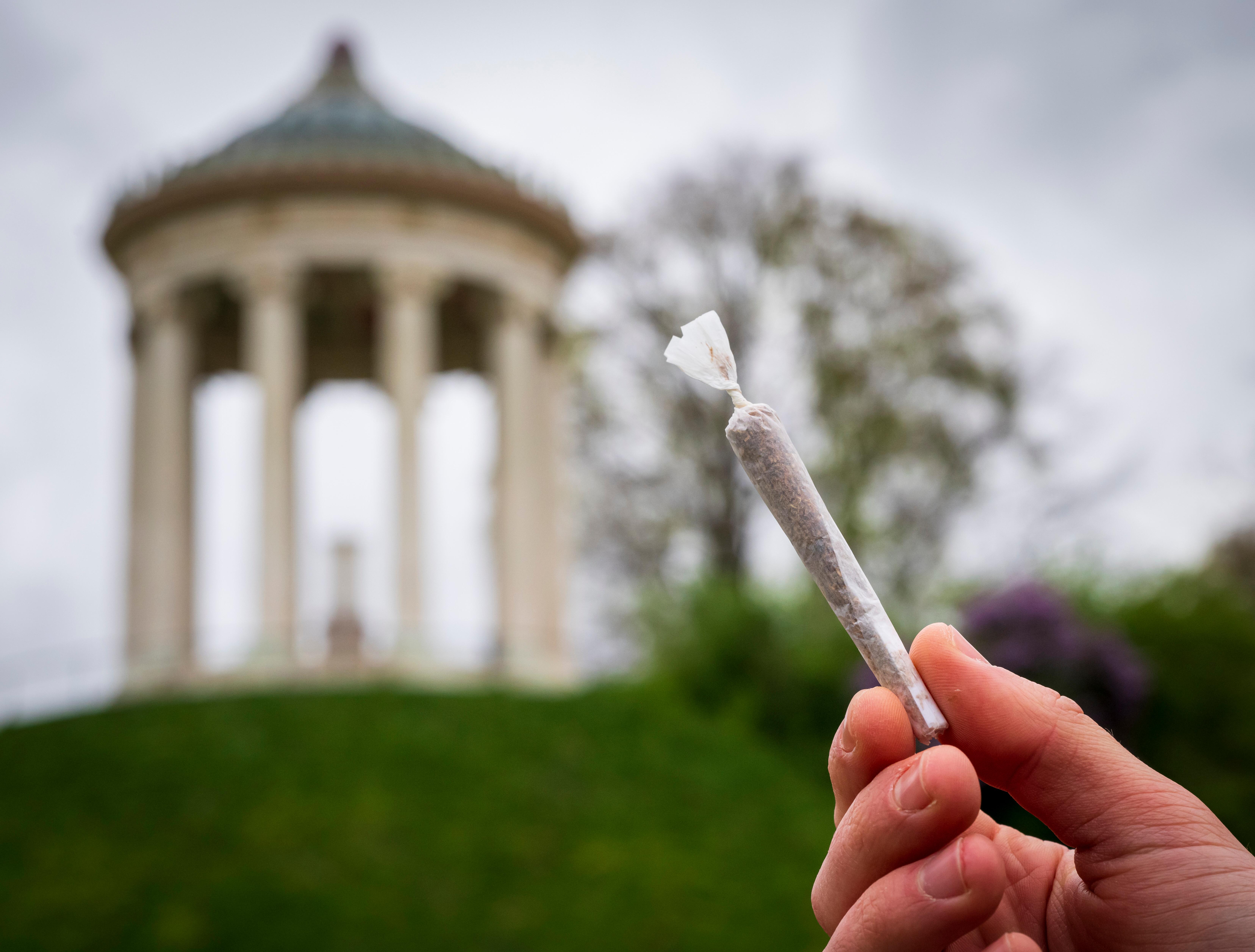 (Archivbild) Ein Mann hält einen Joint vor der Kulisse des Monopteros im Englischen Garten.