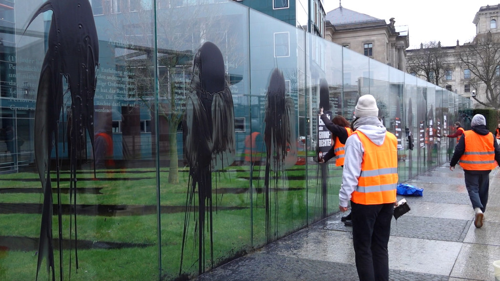 Klimaaktivisten der "Letzten Generation" beschmieren und plakatieren die gläserne Grundgesetz-Skulptur am Bundestag