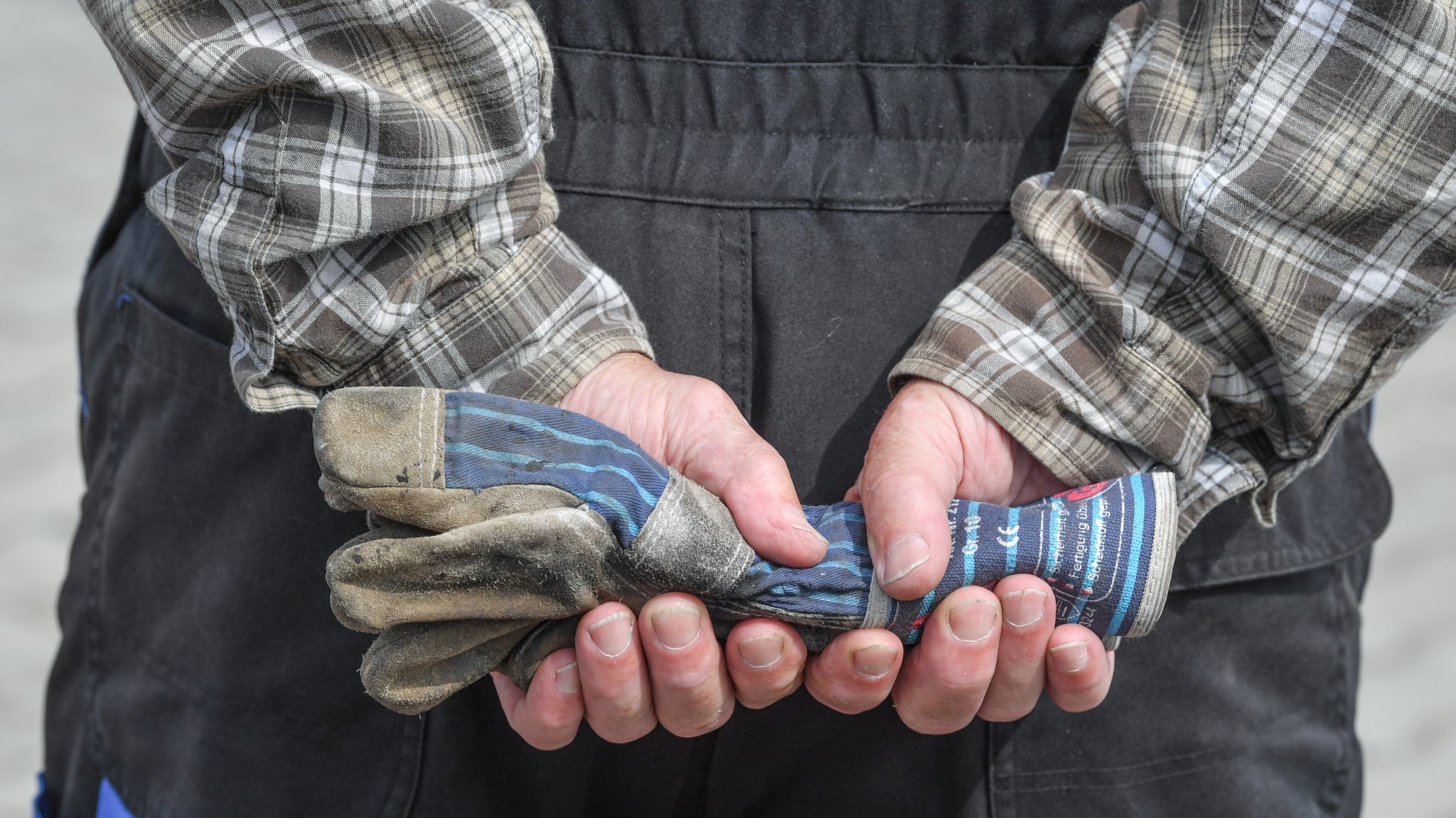 Mann in Latzhose, der hinter seinem Rücken Arbeitshandschuhe in seinen Händen hält | Bild: picture alliance/dpa/dpa-Zentralbild | Patrick Pleul Mann in Latzhose, der hinter seinem Rücken Arbeitshandschuhe in seinen Händen hält