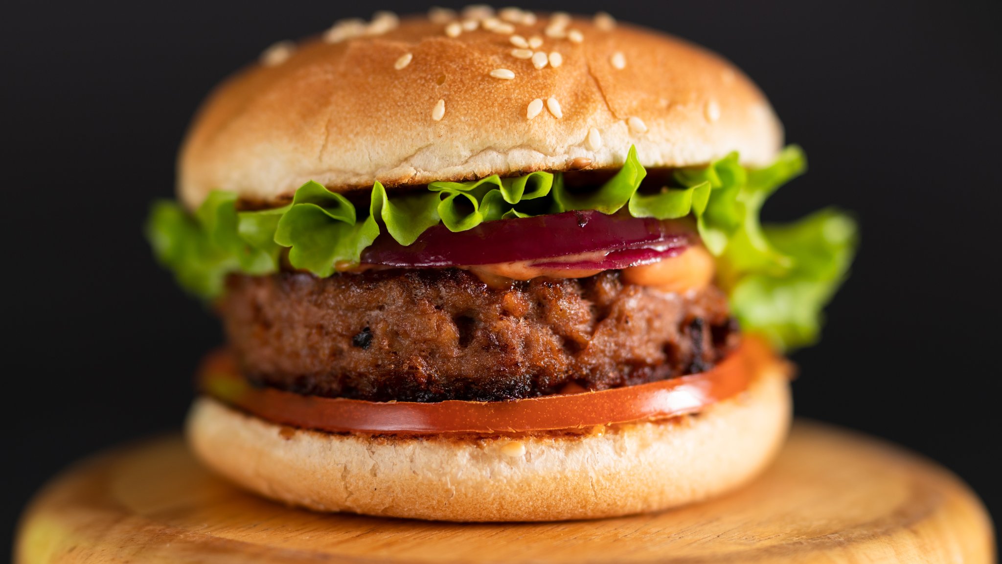 (Symbolbild) Ein Veggie-Burger liegt auf einem Holzteller.