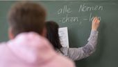 Eine Lehrerin schreibt etwas an die Tafel im Klassenzimmer (Symbolbild) | Bild:pa/dpa/Marijan Murat