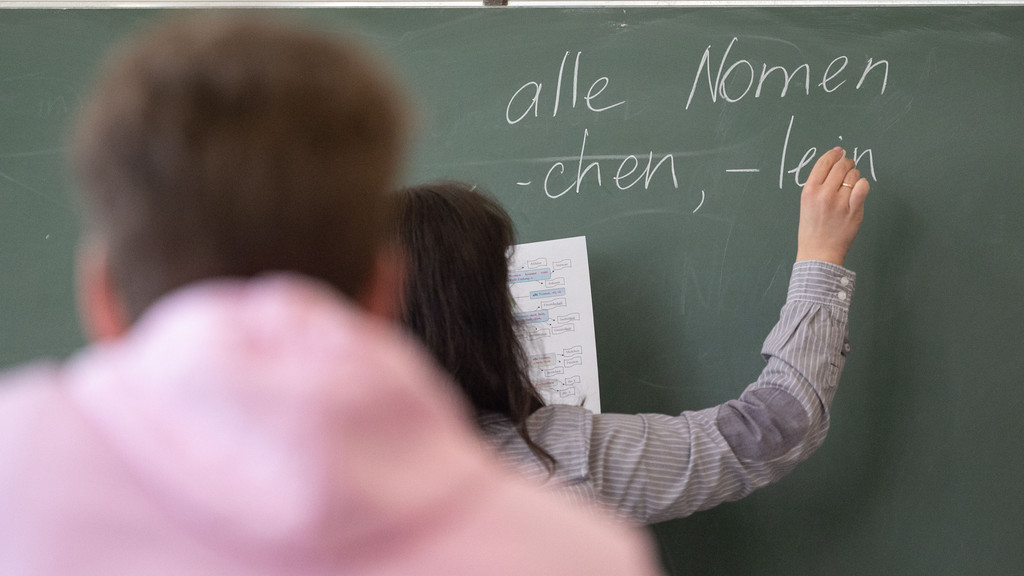 Eine Lehrerin schreibt etwas an die Tafel im Klassenzimmer (Symbolbild)