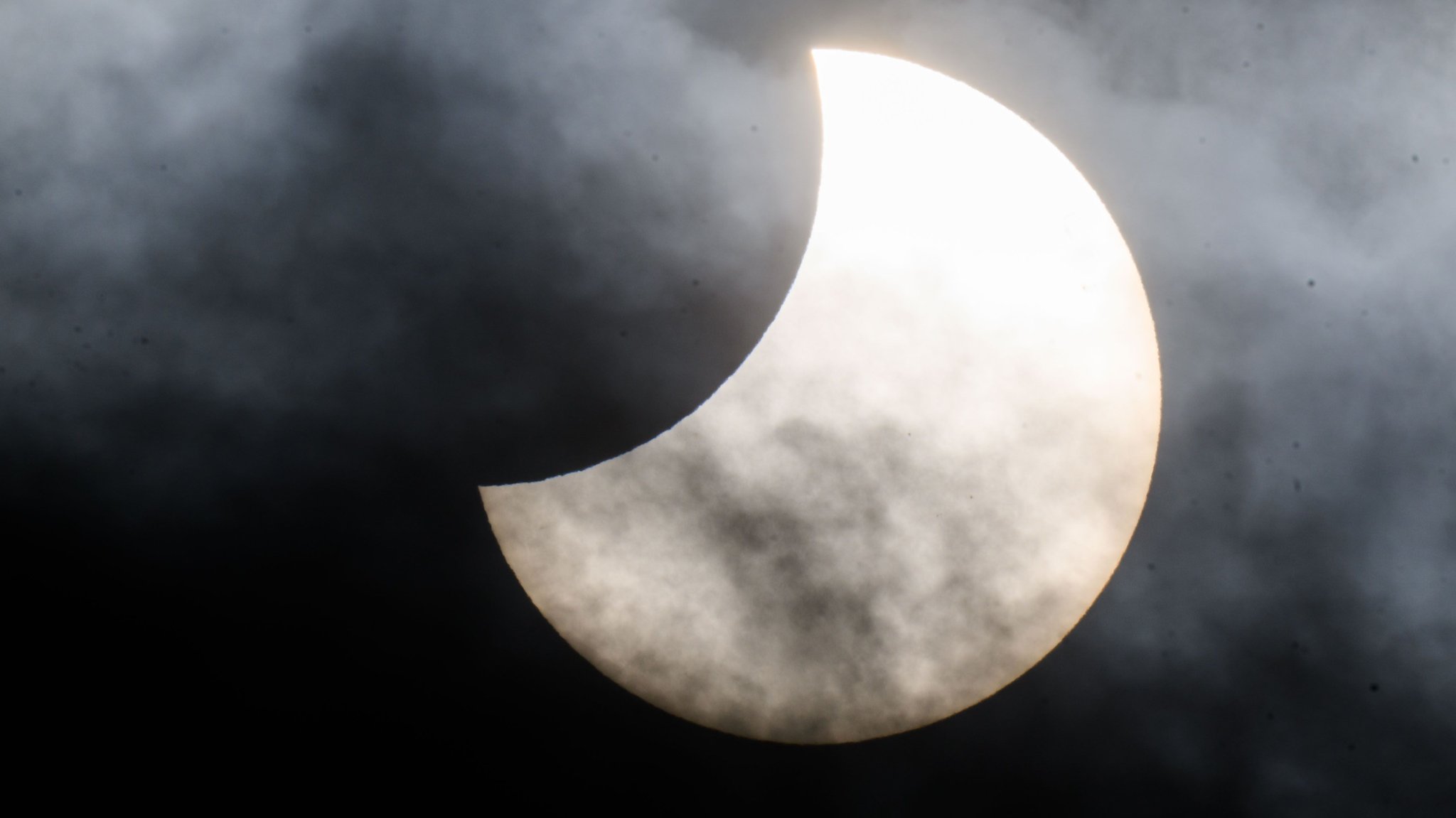 Eine partielle Sonnenfinsternis ist 2022 zwischen Wolken am Himmel zu sehen. | Bild: dpa-Bildfunk/Julian Stratenschulte Eine partielle Sonnenfinsternis ist 2022 zwischen Wolken am Himmel zu sehen.