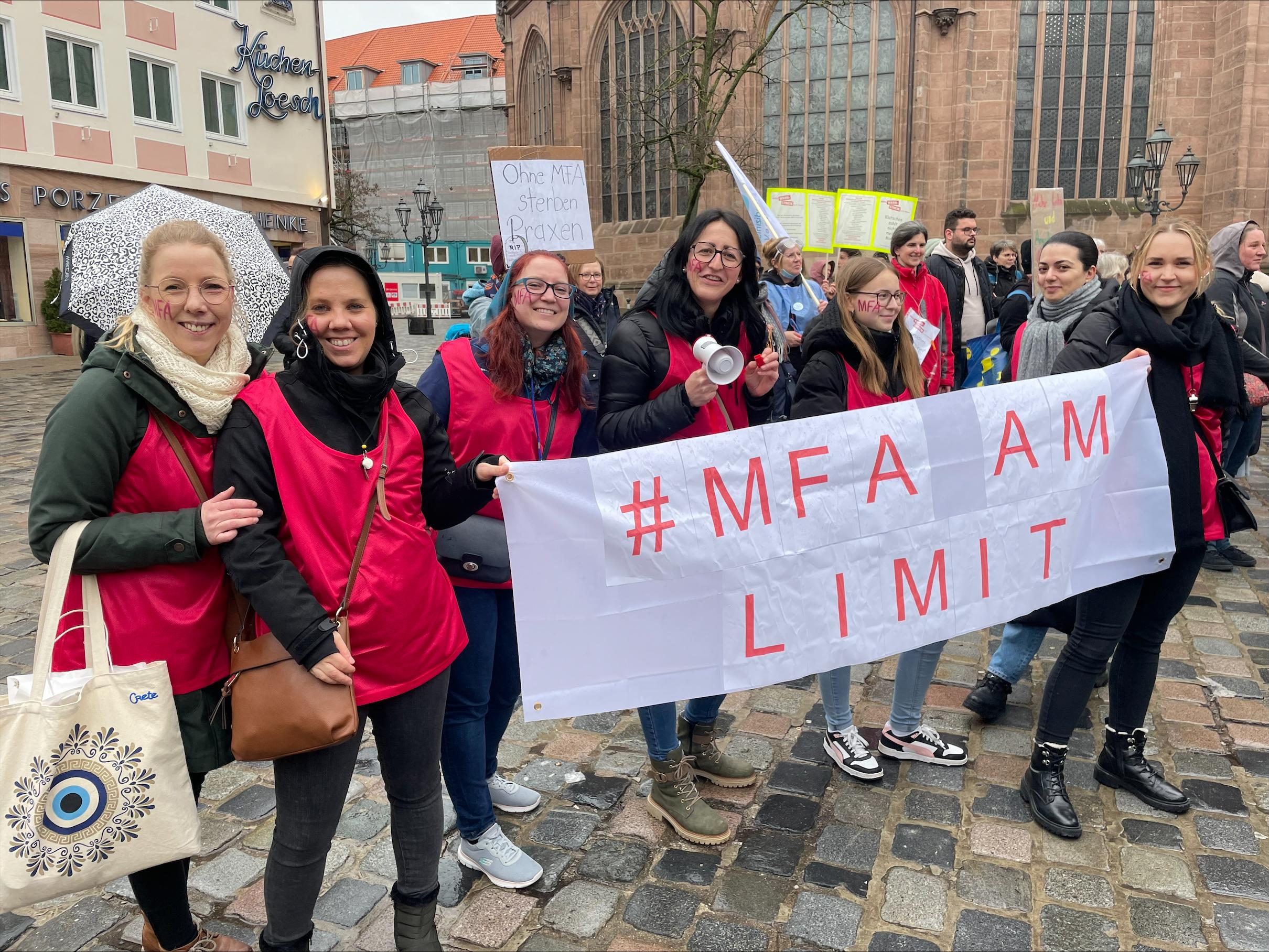 Frauen halten ein Plakat hoch, auf dem steht: "MFA am Limit"