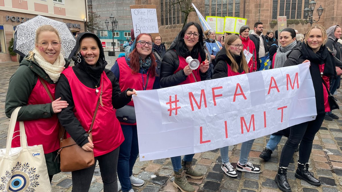 Frauen halten ein Plakat hoch, auf dem steht: "MFA am Limit"