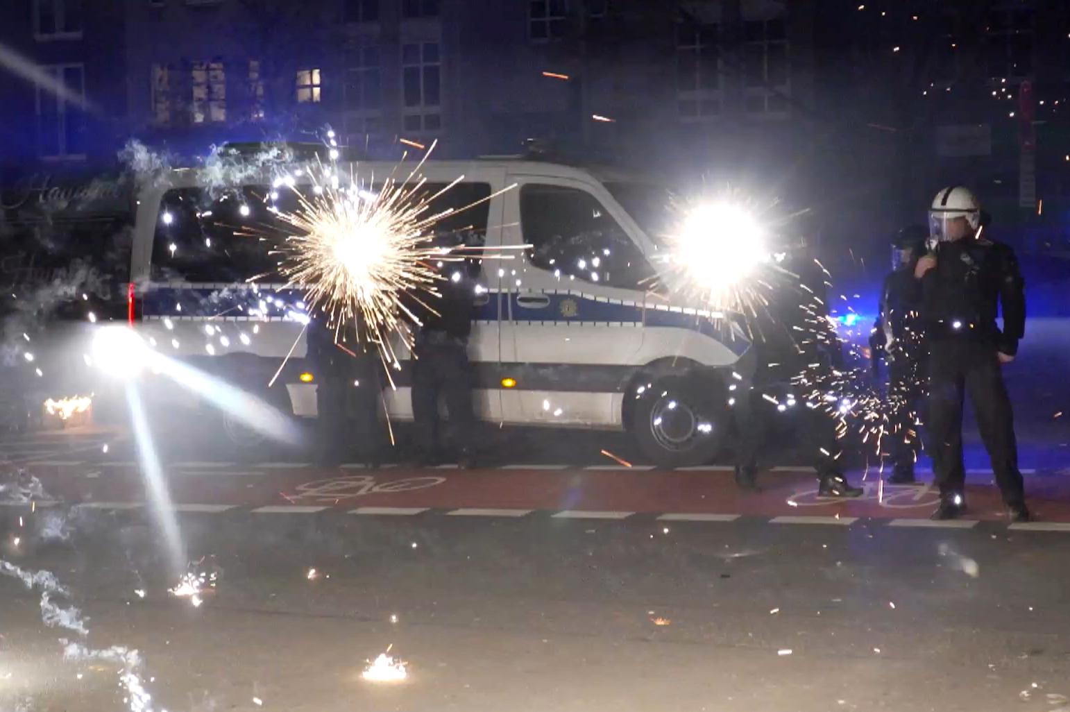Polizeibeamte stehen in der Silvesternacht hinter explodierendem Feuerwerk.