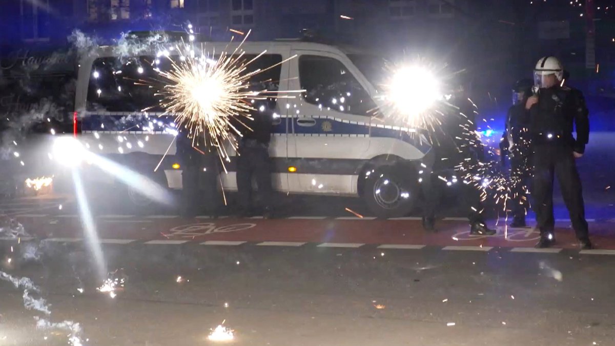Polizeibeamte stehen in der Silvesternacht hinter explodierendem Feuerwerk.