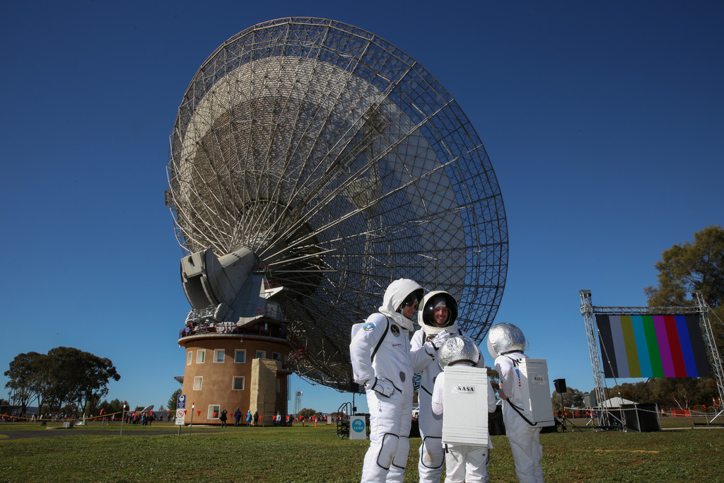 Eine Besuchergruppe steht verkleidet als Astronauten von dem Parkes Teleskop in Australien.