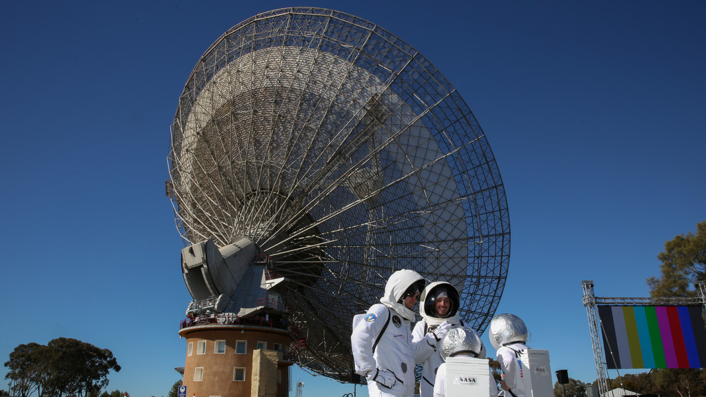 Eine Besuchergruppe steht verkleidet als Astronauten von dem Parkes Teleskop in Australien.