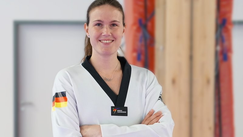 Lorena Brandl mit verschränkten Armen in ihrem Taekwondo-Outfit. | Bild: BR/Patricia Kiel Lorena Brandl mit verschränkten Armen in ihrem Taekwondo-Outfit.