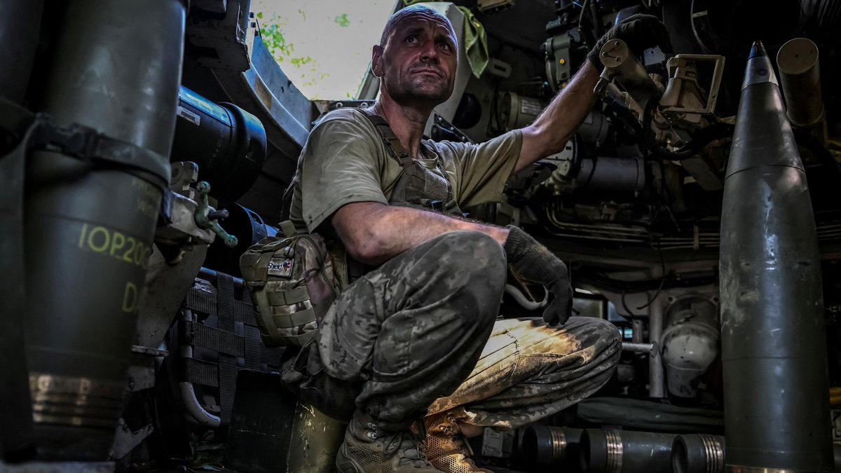 Ein ukrainischer Soldat sitzt zwischen Waffen auf dem Boden