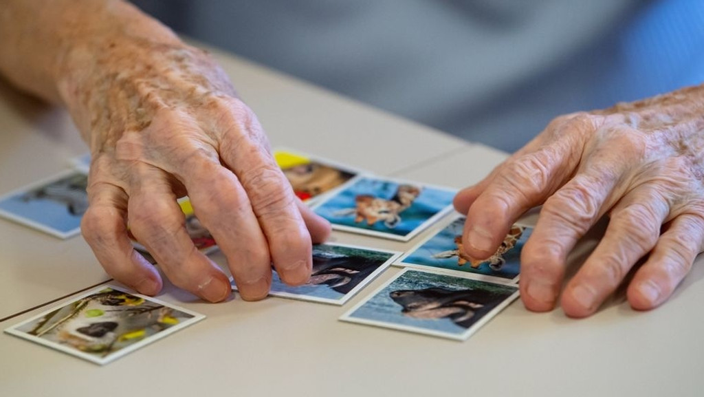 Hände einer alten Frau, die Memory-Karten nebeneinander legt.