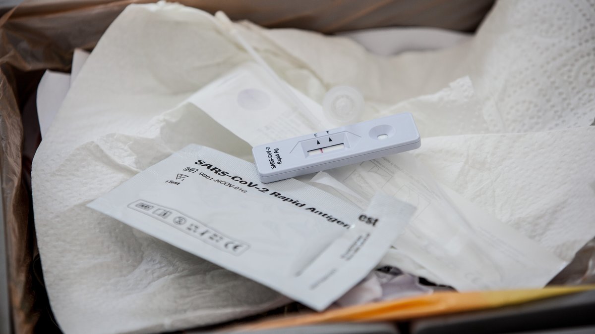 Eine Testkassette von einem negativen SARS-CoV-2 Rapid Antigen Test und die Verpackung des Tests liegen in einem Mülleimer in einem Haushalt.