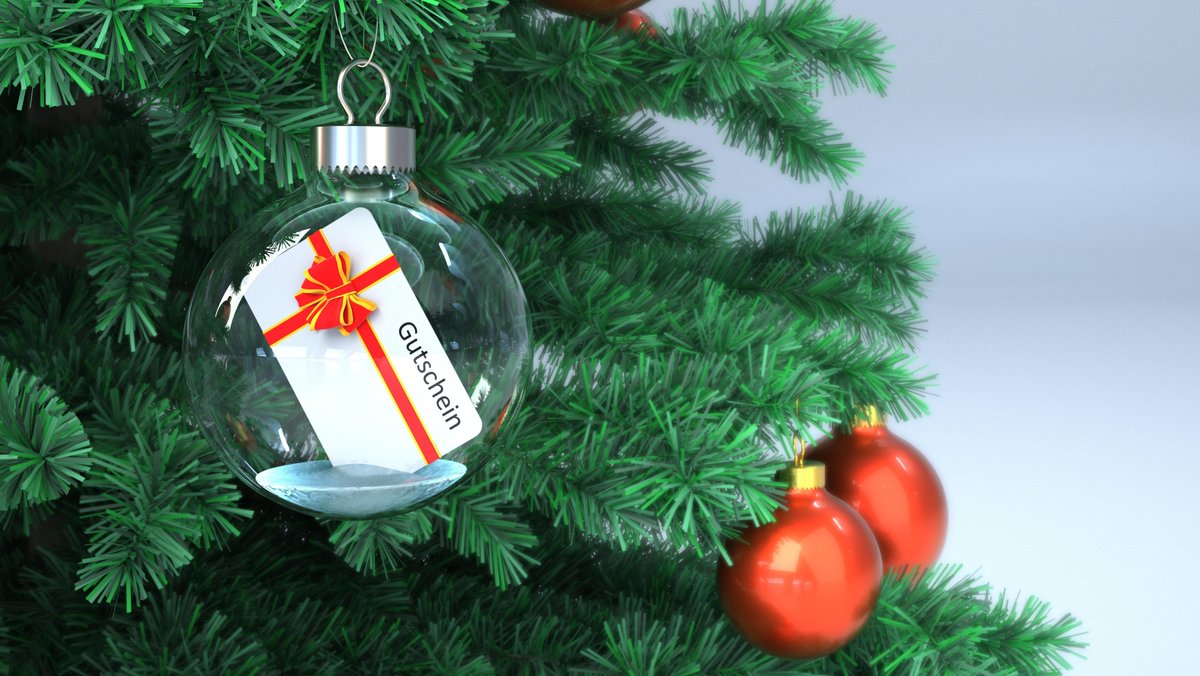 Gutschein in einer transparenten Weihnachtskugel am Tannenbaum