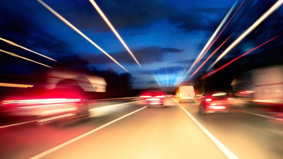 Autos auf der nächtlichen Autobahn mit Lichtspuren.