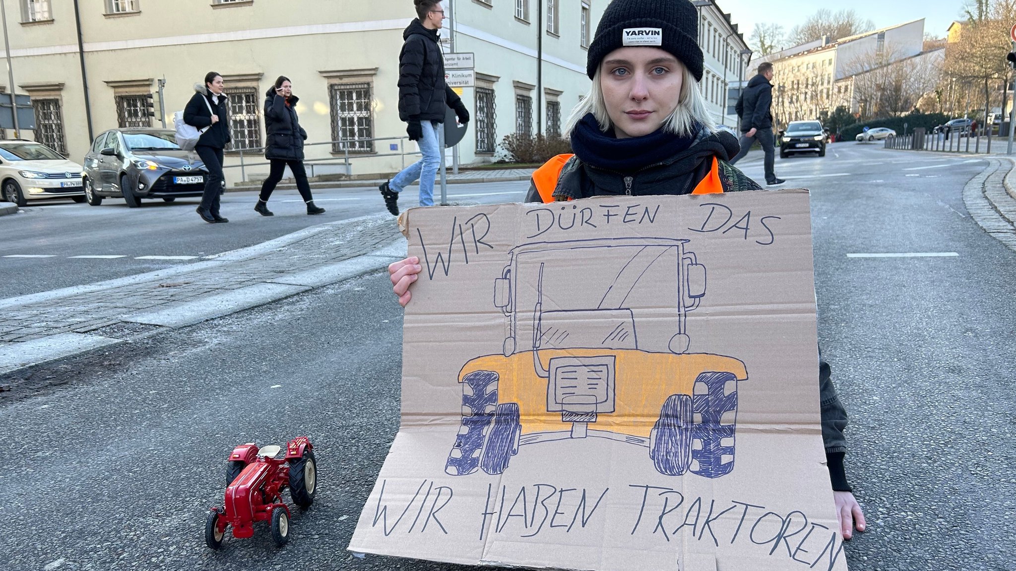 Eine Klimaaktivistin der "Letzten Generation" mit einem Schild: "Wir dürfen das, wir haben Traktoren". 