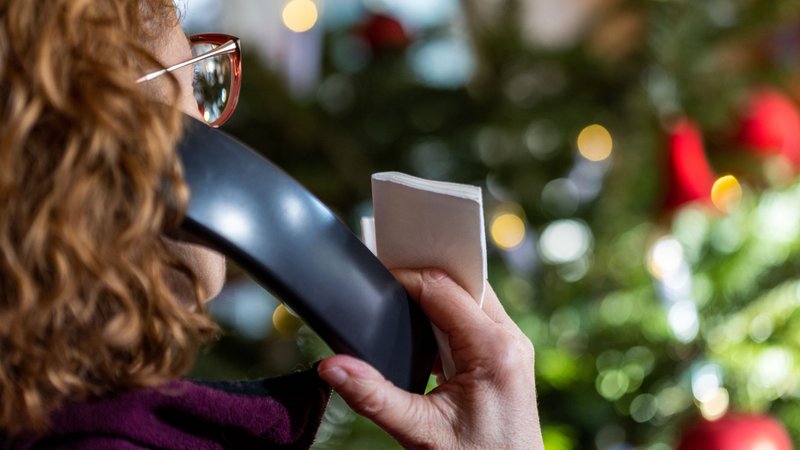 (Symbolbild) Eine Frau sitzt mit dem Telefon vor einem Weihnachtsbaum. | Bild: dpa-Bildfunk/Jens Büttner (Symbolbild) Eine Frau sitzt mit dem Telefon vor einem Weihnachtsbaum.