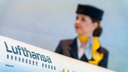 Eine Flugbegleiterin steht hinter einem Modell einer Lufthansamaschine.  | Bild:dpa-Bildfunk/Andreas Arnold