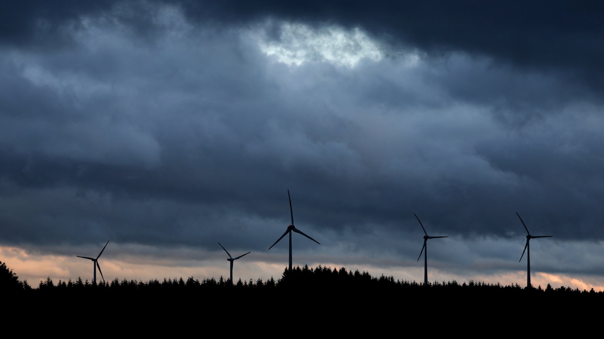 Zu sehen ist ein Windpark in Aitrang im Allgäu unter Regenwolken.