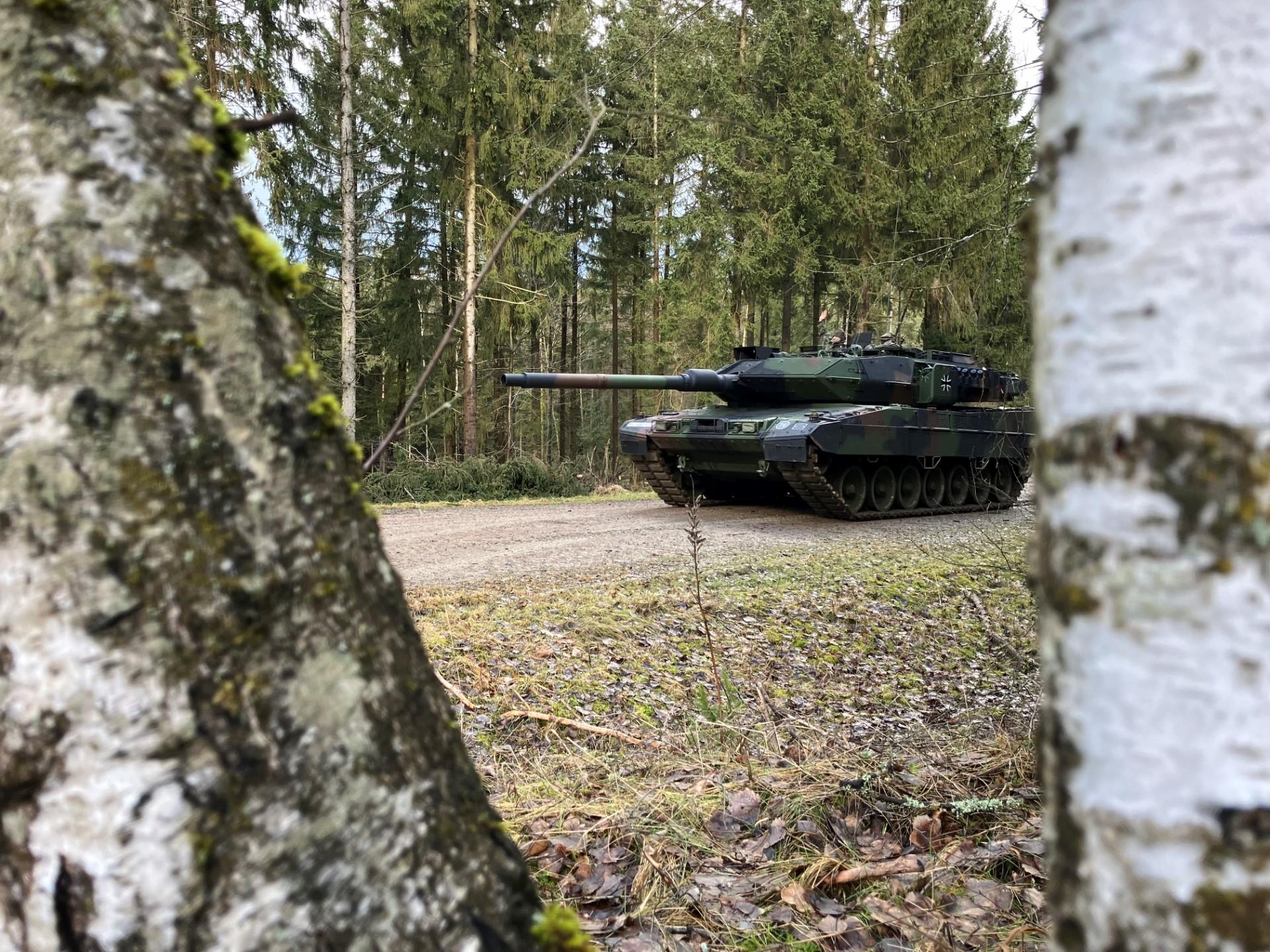 Ein Leopard-Panzer zwischen den Bäumen zu sehen in Vorwärtsfahrt.