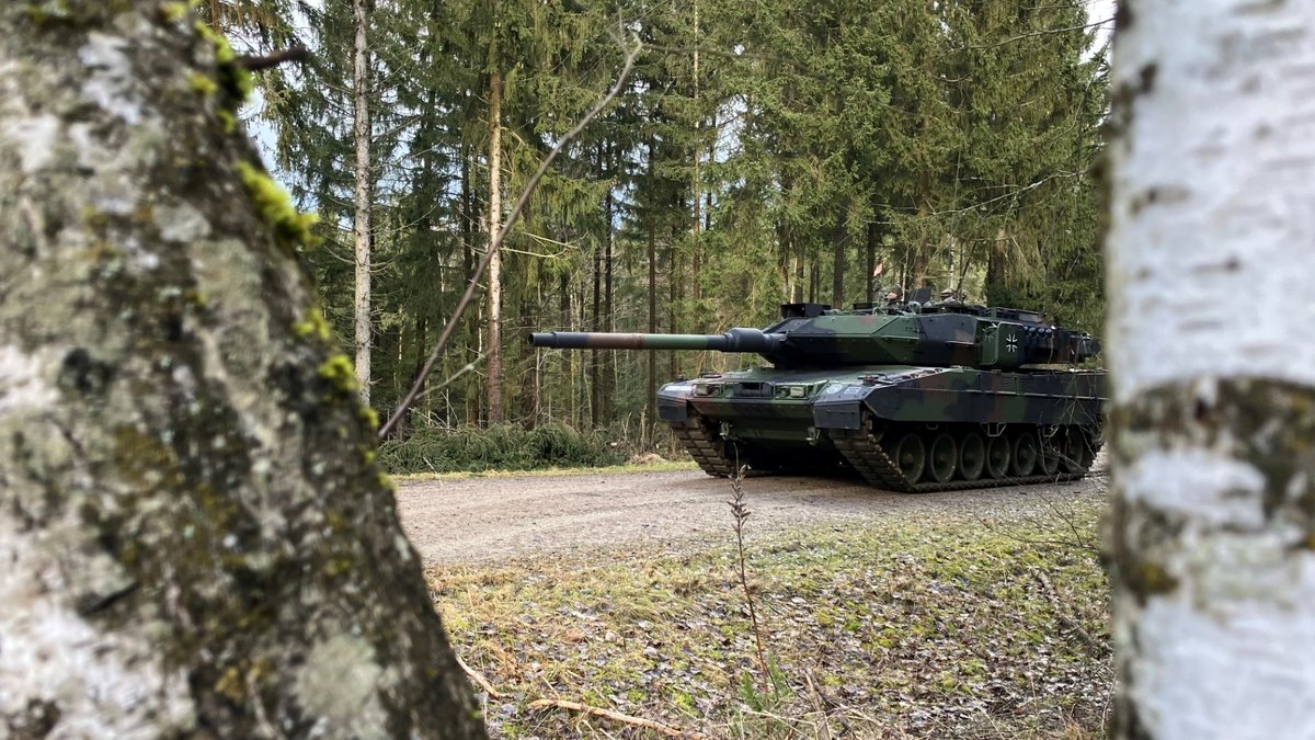 Ein Leopard-Panzer zwischen den Bäumen zu sehen in Vorwärtsfahrt.