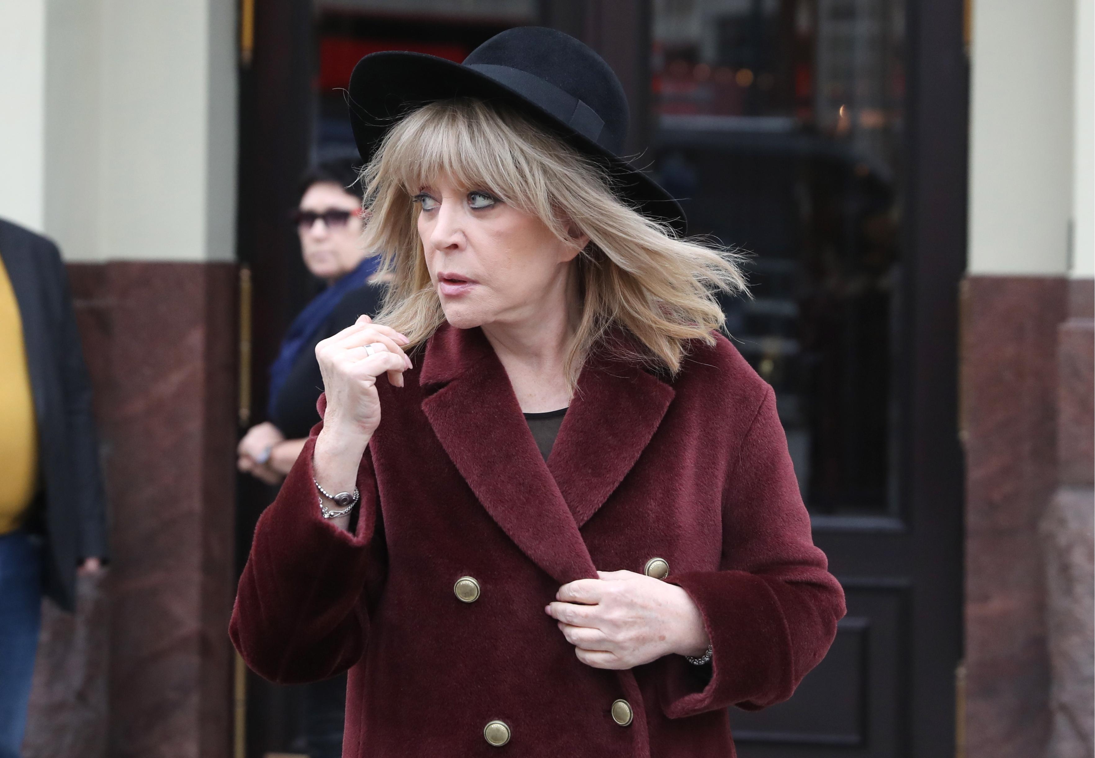 Die Sängerin mit einem schwarzen Hut und in rotem Mantel.