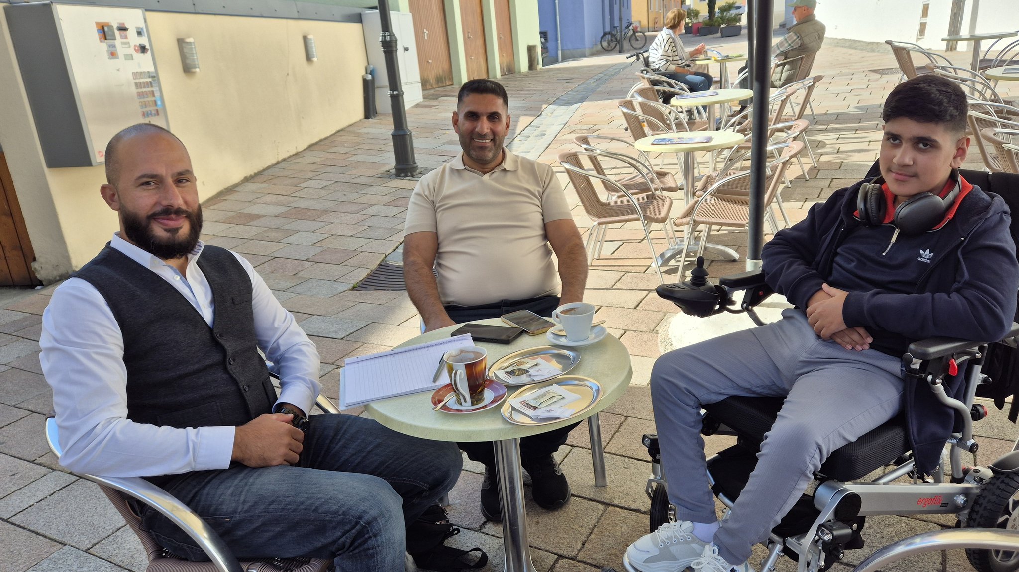 Der Deutsch-Syrer Wadah Aldabel sitzt mit dem zwei Irakern Imad und Mousa an einem Tisch.