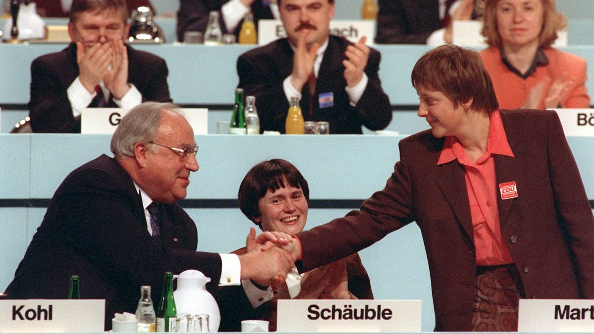 Der damalige Bundeskanzler Helmut Kohl gratuliert seiner neugewählten Stellvertreterin Angela Merkel, während des Parteitags der CDU im Kulturpalast in Dresden; in der Mitte die damalige thüringische Kultusministerin Christine Lieberknecht