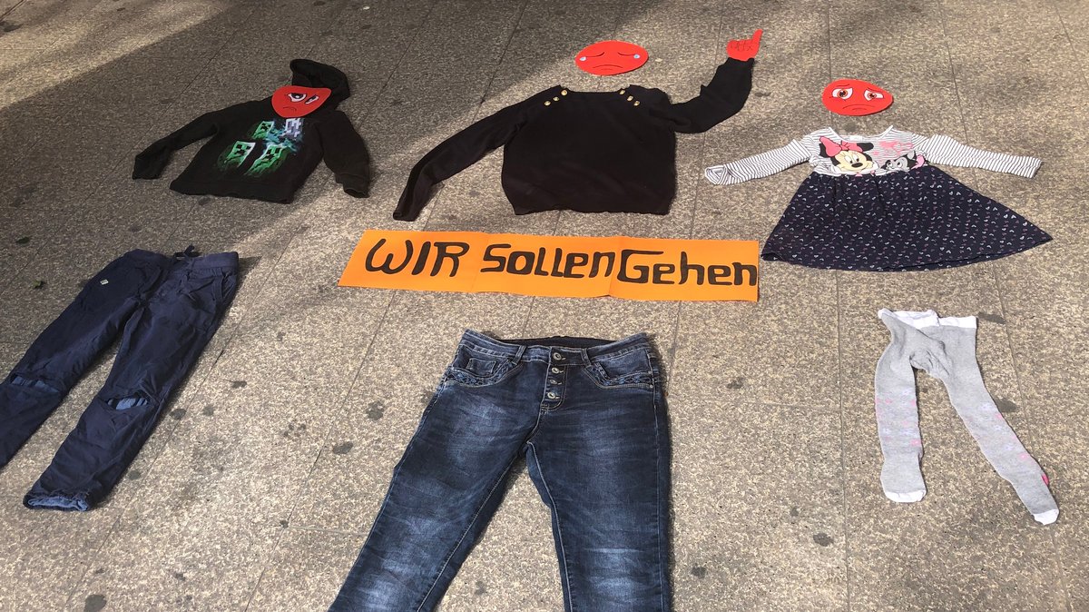 Zu Figuren drapierte Kleidung und weinende Smileys auf dem Gehweg vor dem Rosenheimer H&M
