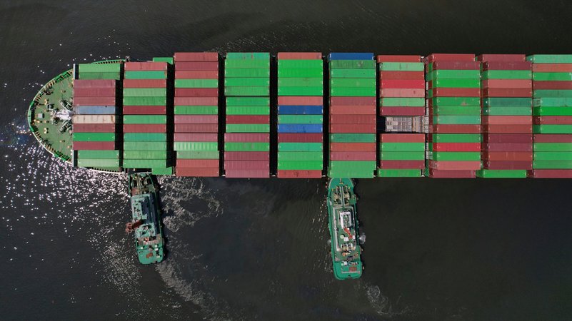 Schlepper helfen einem Containerschiff, das sich auf das Anlegen in einem Containerterminal vorbereitet (Symbolbild) | Bild: dpa-Bildfunk/Aaron Favila Schlepper helfen einem Containerschiff, das sich auf das Anlegen in einem Containerterminal vorbereitet (Symbolbild)