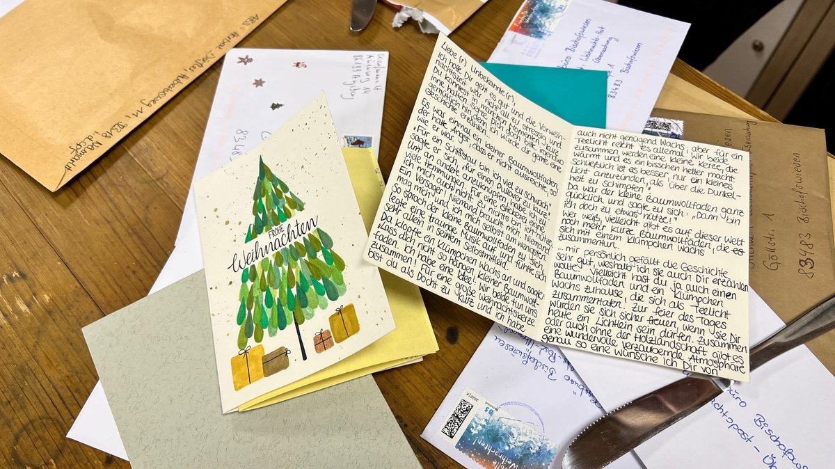 Auf einem Tisch liegen handgeschriebene Weihnachtskarten, die neue Empfänger erhalten.