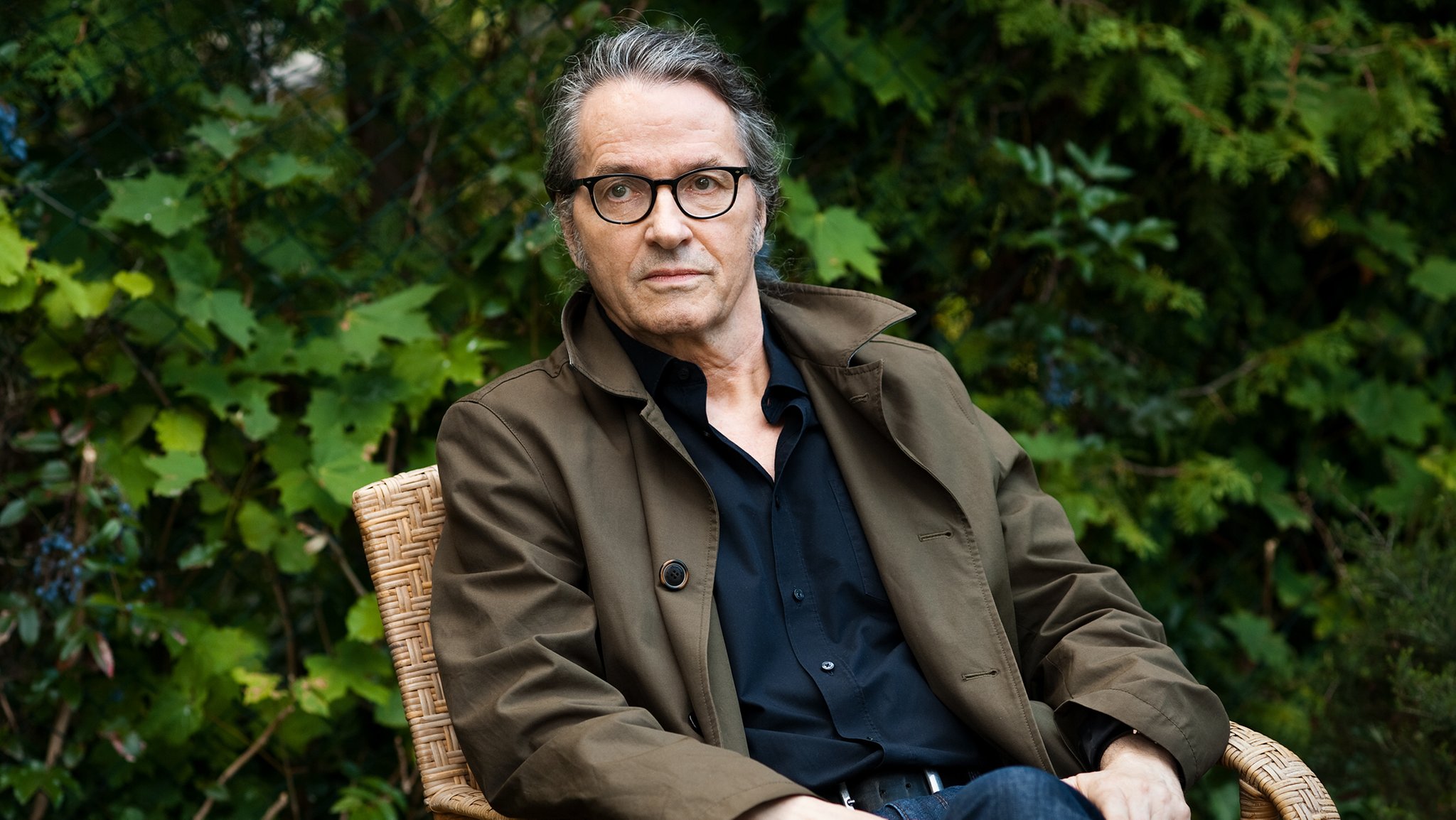 Ralf Rothmann sitzt auf einem Stuhl vor einer Hecke. | Bild: Heike Steinweg/Suhrkamp Verlag Ralf Rothmann sitzt auf einem Stuhl vor einer Hecke.