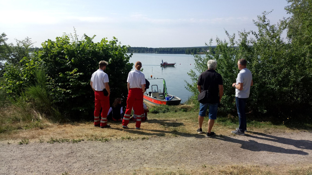 Rettungskräfte stehen am Seeufer