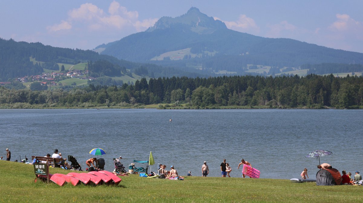 Badegäste erfrischen sich am Ufer des am Alpenrand gelegenen Grüntensees. 