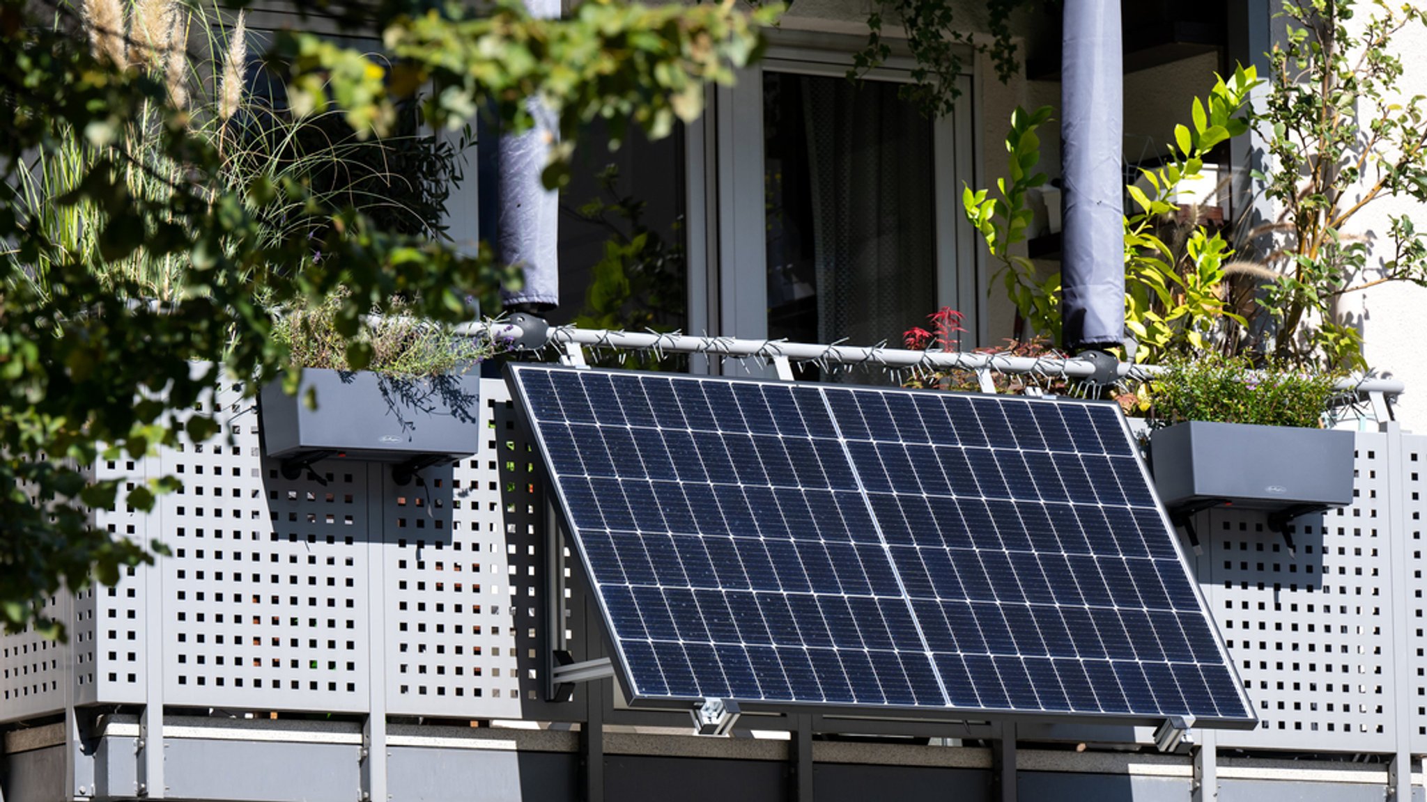 ARCHIV - 22.09.2022, Bayern, München: Eine kleine Solaranlage an einem Balkon eines Mehrparteienhauses angebracht.