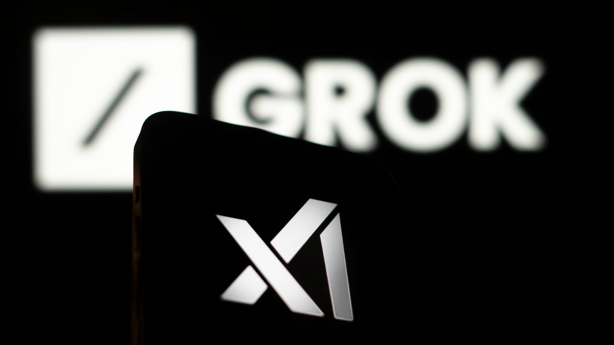Smartphone, das das Logo der KI-Firma xAI zeigt. Im Hintergrund das Logo von "Grok", dem Chatbot von xAI