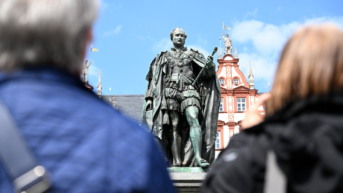 Zwei Touristinnen betrachten die Prinz-Albert-Statue auf dem Marktplatz in Coburg.