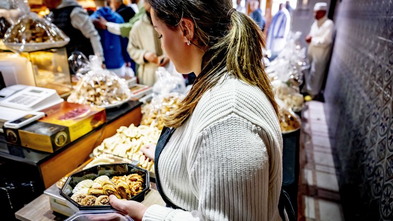 Eine Frau füllt eine Schale mit Süßgebäck. | Bild: picture alliance / ANP | Robin Utrecht Eine Frau füllt eine Schale mit Süßgebäck.