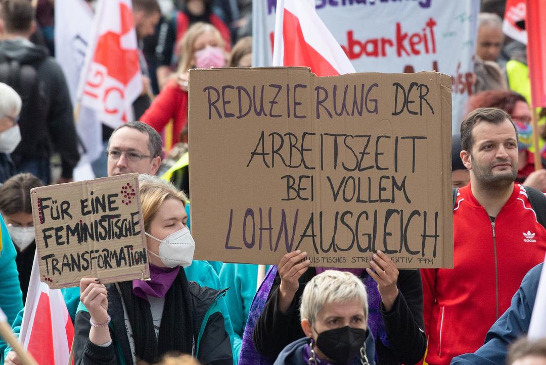 01.05.2022, Hessen, Frankfurt/Main: «Reduzierung der Arbeitszeit bei vollem Lohnausgleich» steht auf dem Plakat einer Frau bei der Mai-Kundgebung der Gewerkschaften in Frankfurt am Main.