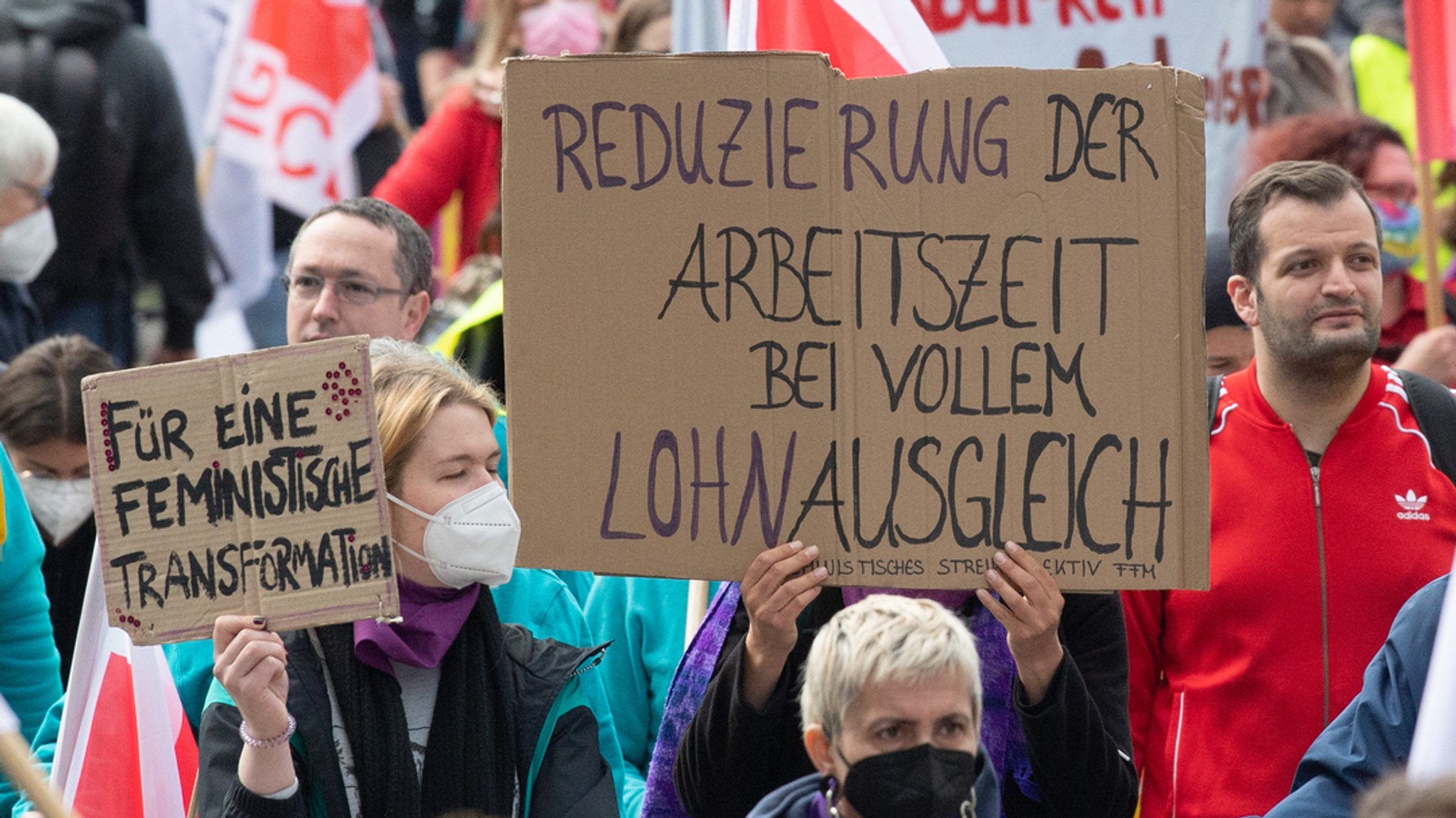 01.05.2022, Hessen, Frankfurt/Main: «Reduzierung der Arbeitszeit bei vollem Lohnausgleich» steht auf dem Plakat einer Frau bei der Mai-Kundgebung der Gewerkschaften in Frankfurt am Main.