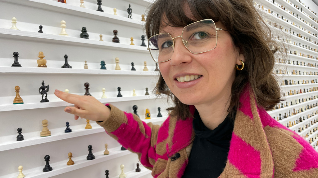 Theres Rohde, Direktorin des Museums für konkrete Kunst steht in ihrer aktuellen Ausstellung "Hängepartie" vor einer Wand voller Schachfiguren.