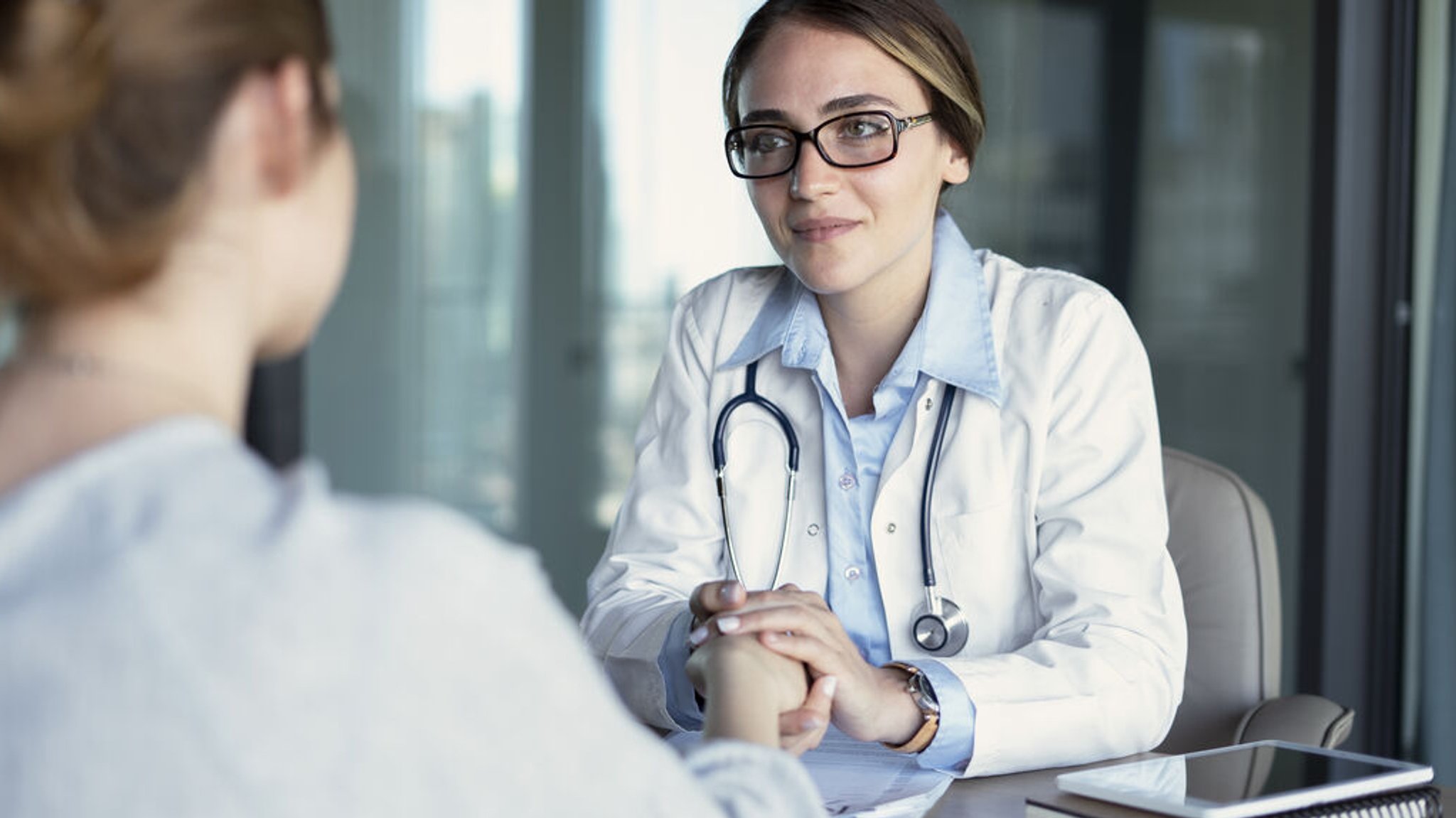 Eine Ärztin spricht mit ihrer Patientin und hält ihre Hand.