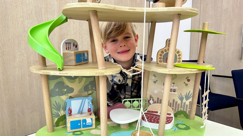 Ein kleiner Junge schaut hinter einem Puppenhaus aus Holz samt Rutsche und Seilzug hervor. | Bild: BR/Michael Reiner Ein kleiner Junge schaut hinter einem Puppenhaus aus Holz samt Rutsche und Seilzug hervor.